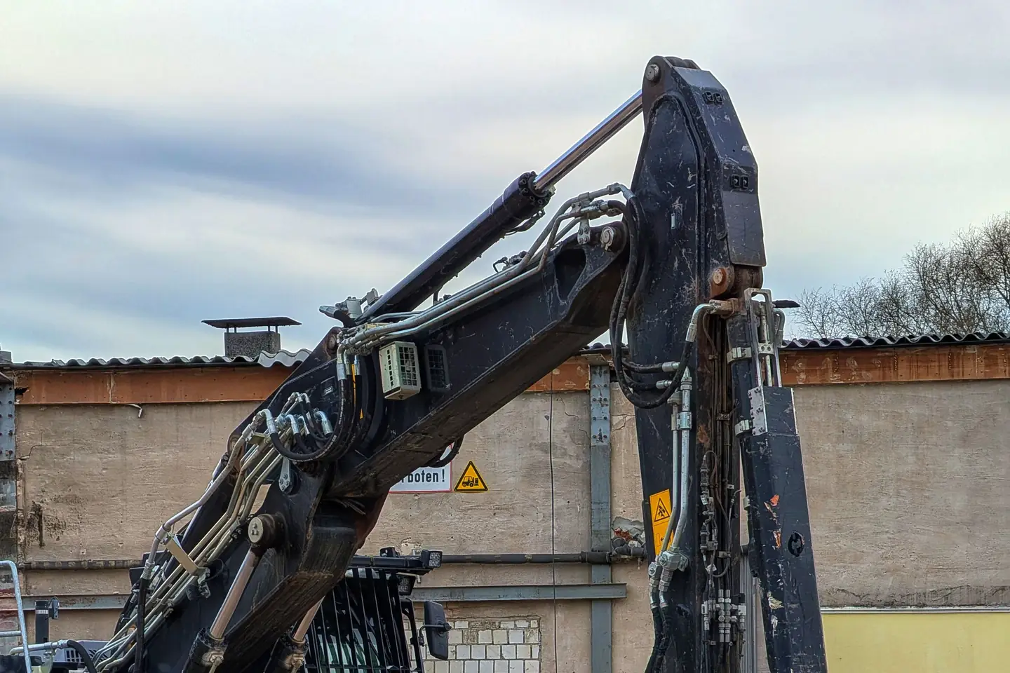 Excavator with a bucket beside broken concrete debris at a demolition site